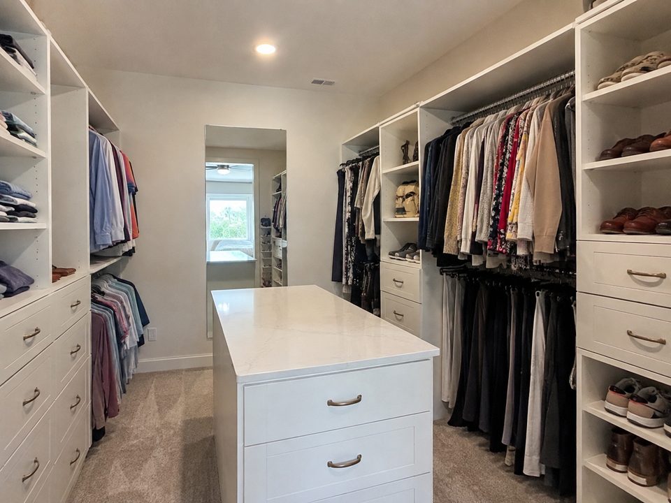 Walk-in closet system with double hanging sections, a drawer island, and shoe shelving
