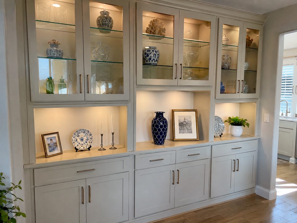 Lit glass-front display cabinets with painted frames and adjustable glass shelving