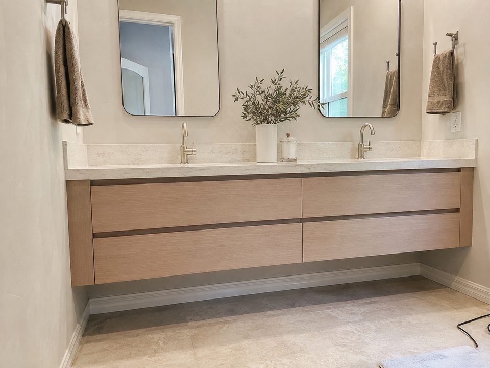 Floating oak bathroom vanity with an integrated counter and wall-mounted mirrors