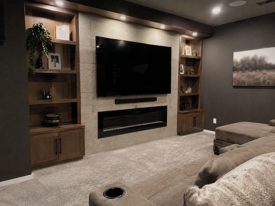 Media room built-ins with a recessed television, fireplace, and walnut display shelving